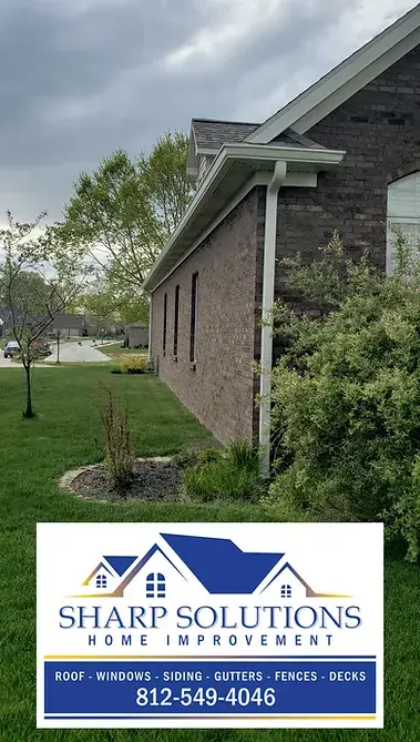 Side of a brick house with new gutter and downspout with Sharp Solutions Home Improvement Logo